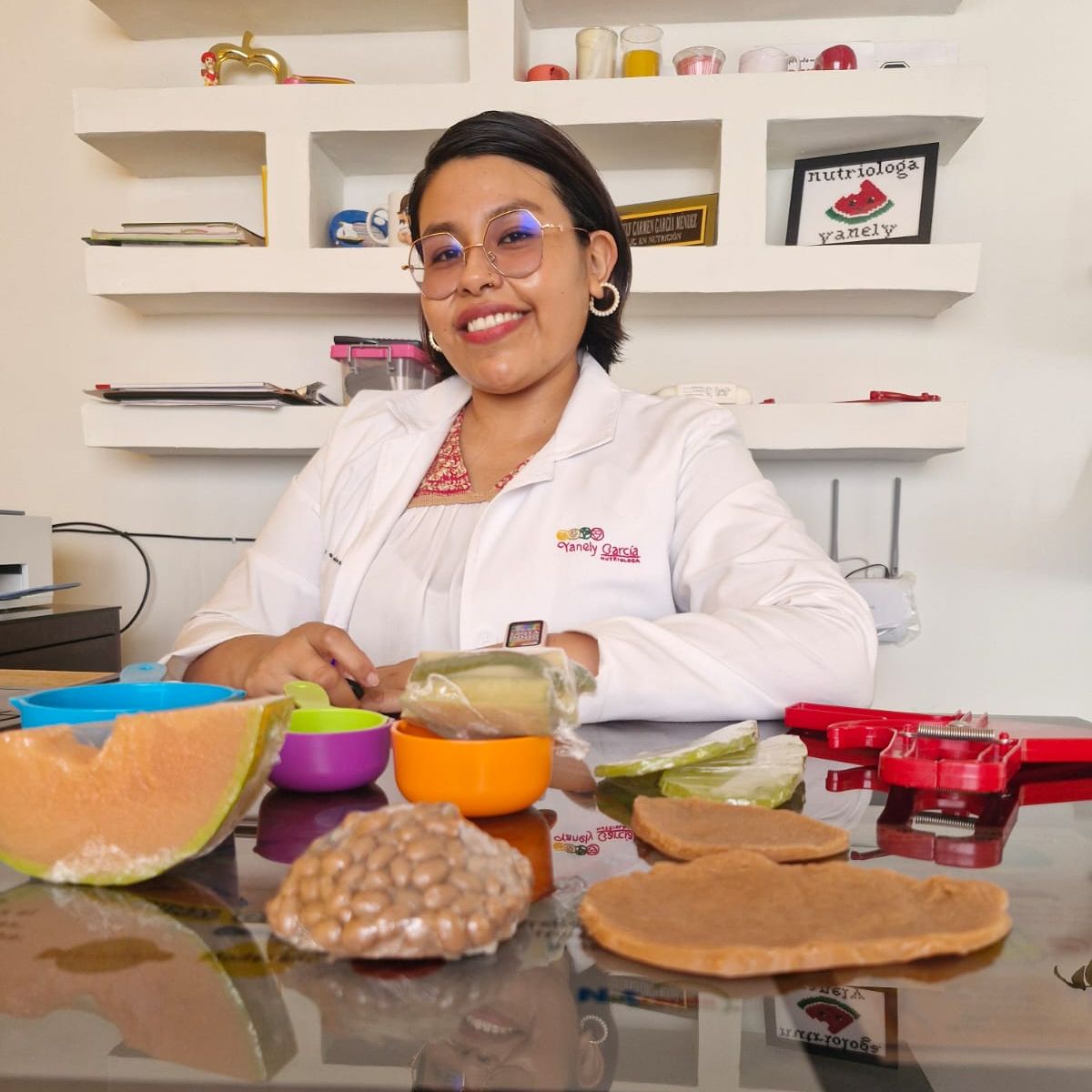 Yanely García en su consultorio, con bata y materiales de trabajo
