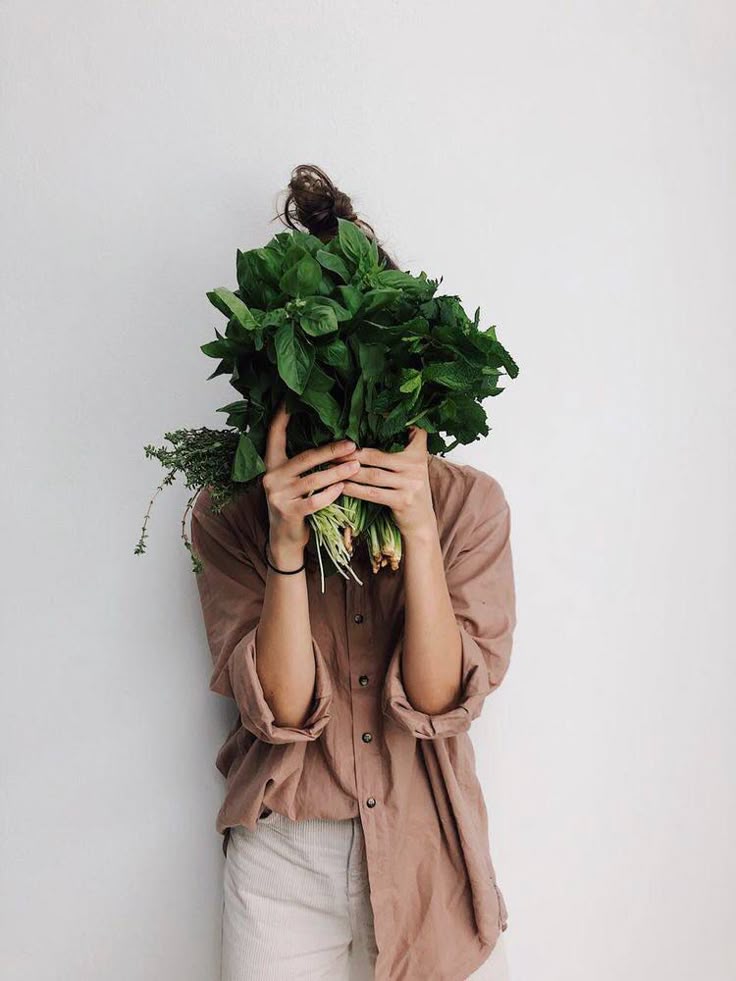 Mujer sosteniendo un manojo de hierbas frescas como albahaca y menta